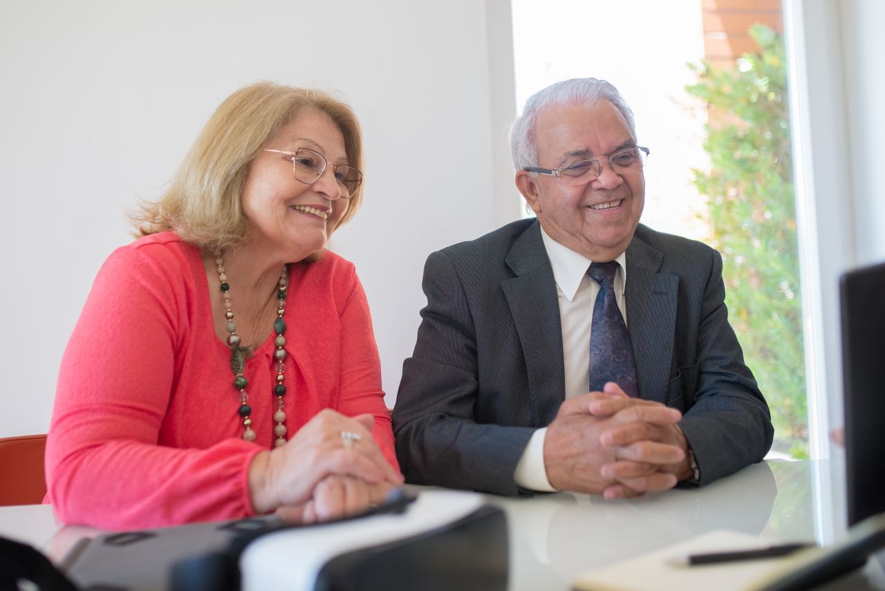 Happy elderly couple in formal attire at a business meeting indoors.